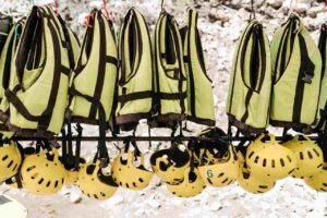 A flat lay arrangement of essential water sports gear including high flotation life jackets safety helmets and quick dry clothing layers for premium jinja adventure packages