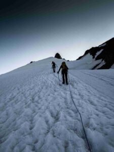 A group of alpine mountaineers managing safety ropes and crampons to conquer a steep vertical ice wall during a technical margherita peak climbing expedition