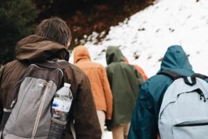 A professional top down flat lay of winter mountaineering apparel including waterproof gore tex outer shells thermal layers and mid ankle trail boots for a mountains of the moon trekking tour
