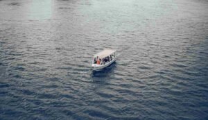 A private covered motorized watercraft launch boat charter cruising down the calm waters of the Nile during a source of the nile tour jinja day trip