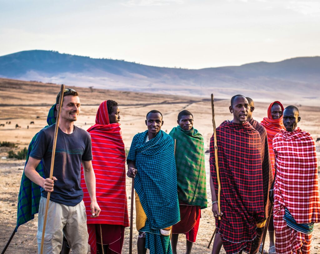 pexels-photo-667202-667202 A traveler joins Masai tribe members on a sunny day in an open African landscape.